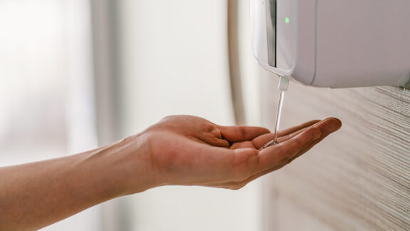 Nainen käyttää käsidesiautomaattia.